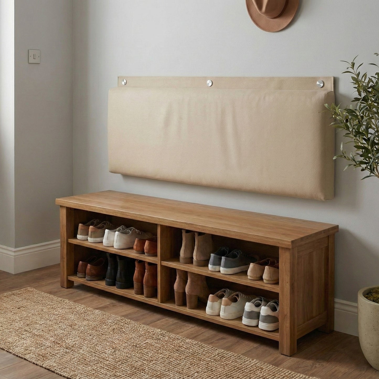 Rechteckiges, gepolstertes Wandkissen in Beige, das mit drei runden silbernen Metallkappen als Rückenlehne an der Wand über einer hölzernen Schuhbank montiert ist, um im Eingangsbereich Komfort zu bieten.